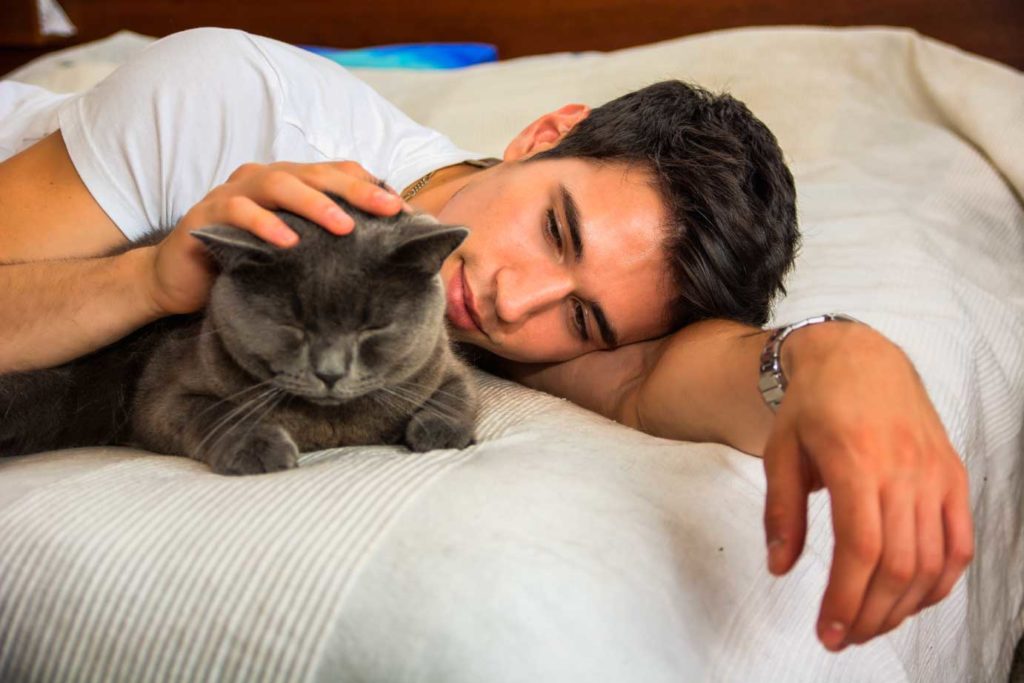 chico joven con gato en la cama